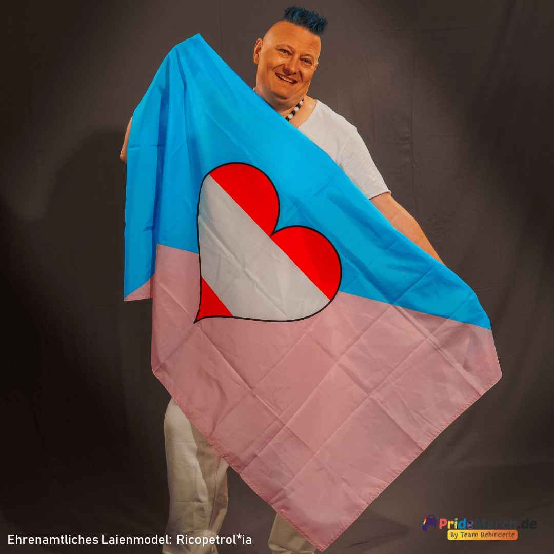In der Datei ricopetrolia-laienmodel-pridemerch-by-team-behinderte_5.jpg zeigt unser ehrenamtliches Model Gina Petrolia (Ricopetrolia) stolz die geöffnete Ageplay Pride Flagge (oft als Femboy-Herz-Flagge gesucht). Zu sehen ist die markante diagonale Teilung in Hellblau und Rosa mit dem gestreiften Herz im Zentrum.
