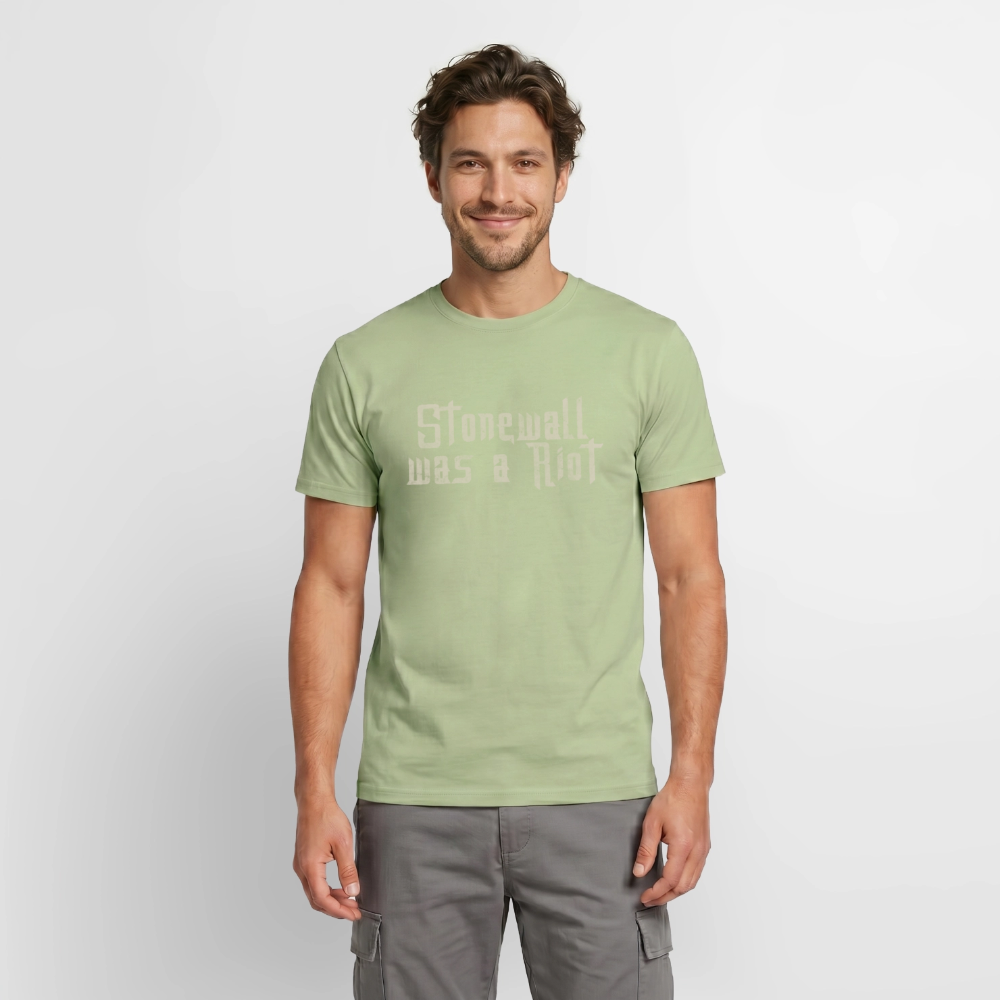 Ein männliches Model präsentiert das sage-grüne Aktivismus-Shirt von PrideLAB. Die verwitterte Stencil-Typografie erinnert an den historischen Widerstand von 1969 und setzt ein klares Statement für LGBTIQ-Rechte.