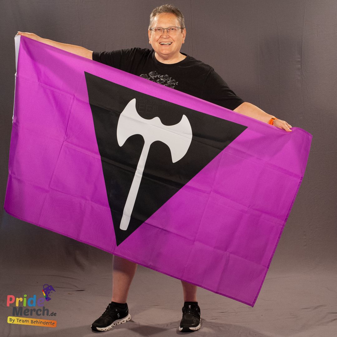 Das ehrenamtliche Laienmodell Beate Pellegrino hält die violette Labrys-Flagge mit der lesbischen Doppelaxt im Fotostudio freudig lachend vor sich ausgebreitet. Das detailreiche, kontraststarke Motiv wird frontal präsentiert.