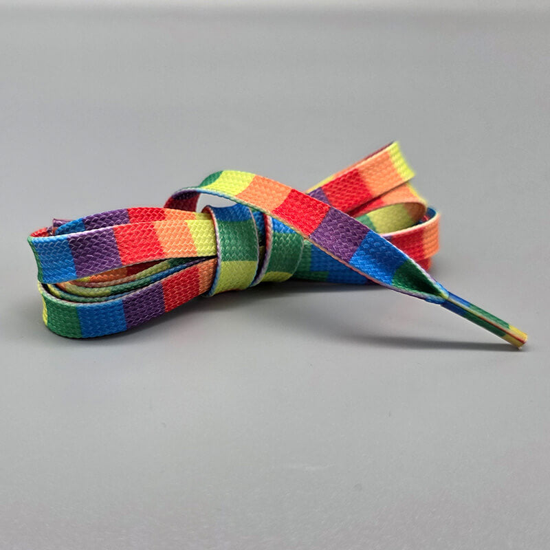 Pride Schnürsenkel in der Variante "Regenbogen senkrecht". Die flachen Schnürsenkel sind in den Farben des Regenbogens gehalten: Rot, Orange, Gelb, Grün, Blau und Violett. Die Farben sind in senkrechten Streifen angeordnet. Das Bild zeigt die Schnürsenkel auf einem hellgrauen Hintergrund.