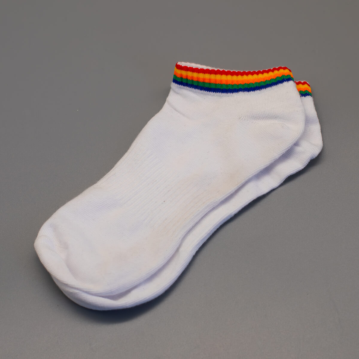 Am obersten Rand dieser weißen Sneakersocken prangt das unmissverständliche Statement für Vielfalt als umlaufendes Regenbogenband. Das Produktbild ist ohne Hintergrund im Flatlay-Stil angelegt und bietet ein kontrastreiches Basic für die Community.