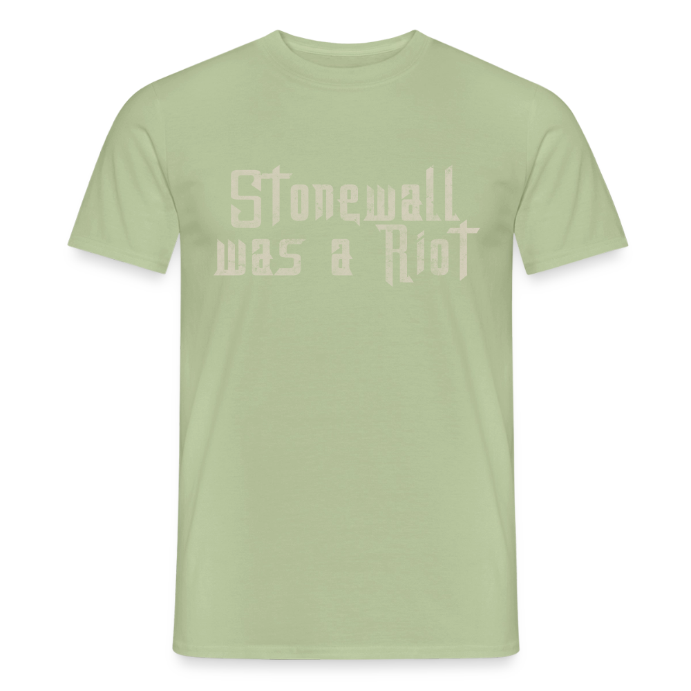 Freigestelltes T-Shirt in der Farbe Sage (helles Salbeigrün). Der helle Schriftzug „Stonewall was a Riot“ ist in markanter Stencil-Optik mit Used-Look-Textur zentriert auf der Brust platziert.