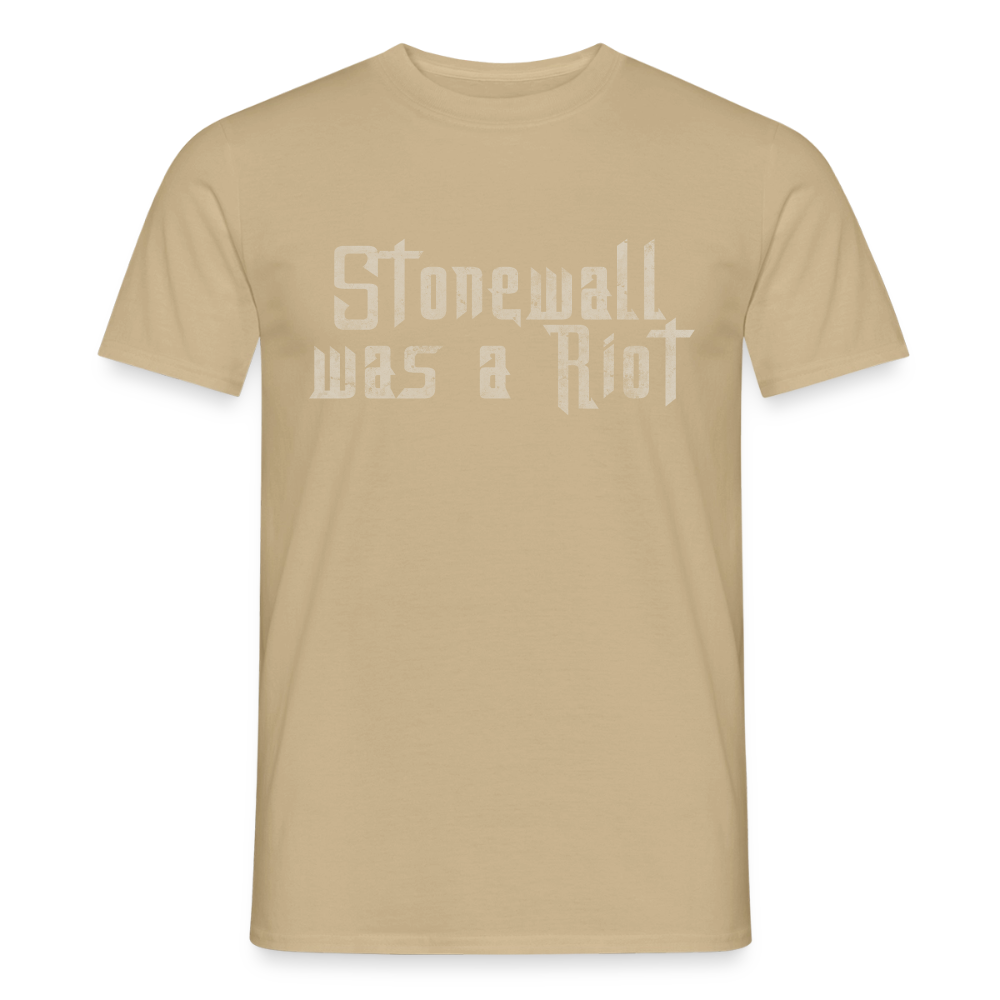 Freigestelltes sandbeiges T-Shirt mit hellem Stencil-Print. Die verwitterte Optik von „Stonewall was a Riot“ erinnert an die revolutionären Flugblätter von 1969.