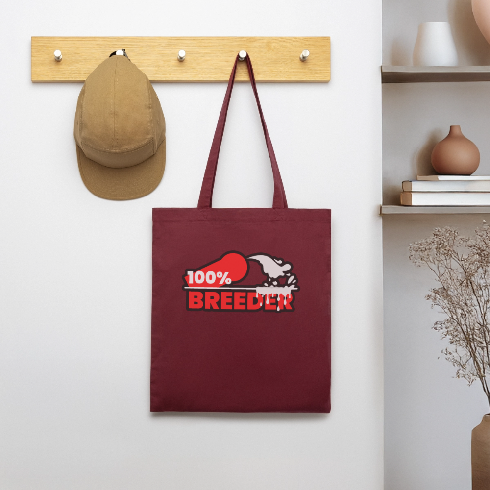 Burgunderroter Bio-Stoffbeutel mit dem kraftvollen "100% Breeder" Kink Fetish Design hängt an einer Garderobe – starkes Statement für dominante Tops und aktive Player