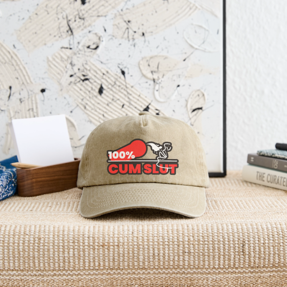 Vintage beige Cap mit dem direkten "100% Cum Slut" Kink Design auf einer Ablage – für Bottoms, die ihre devote und lustvolle Seite stolz nach außen tragen
