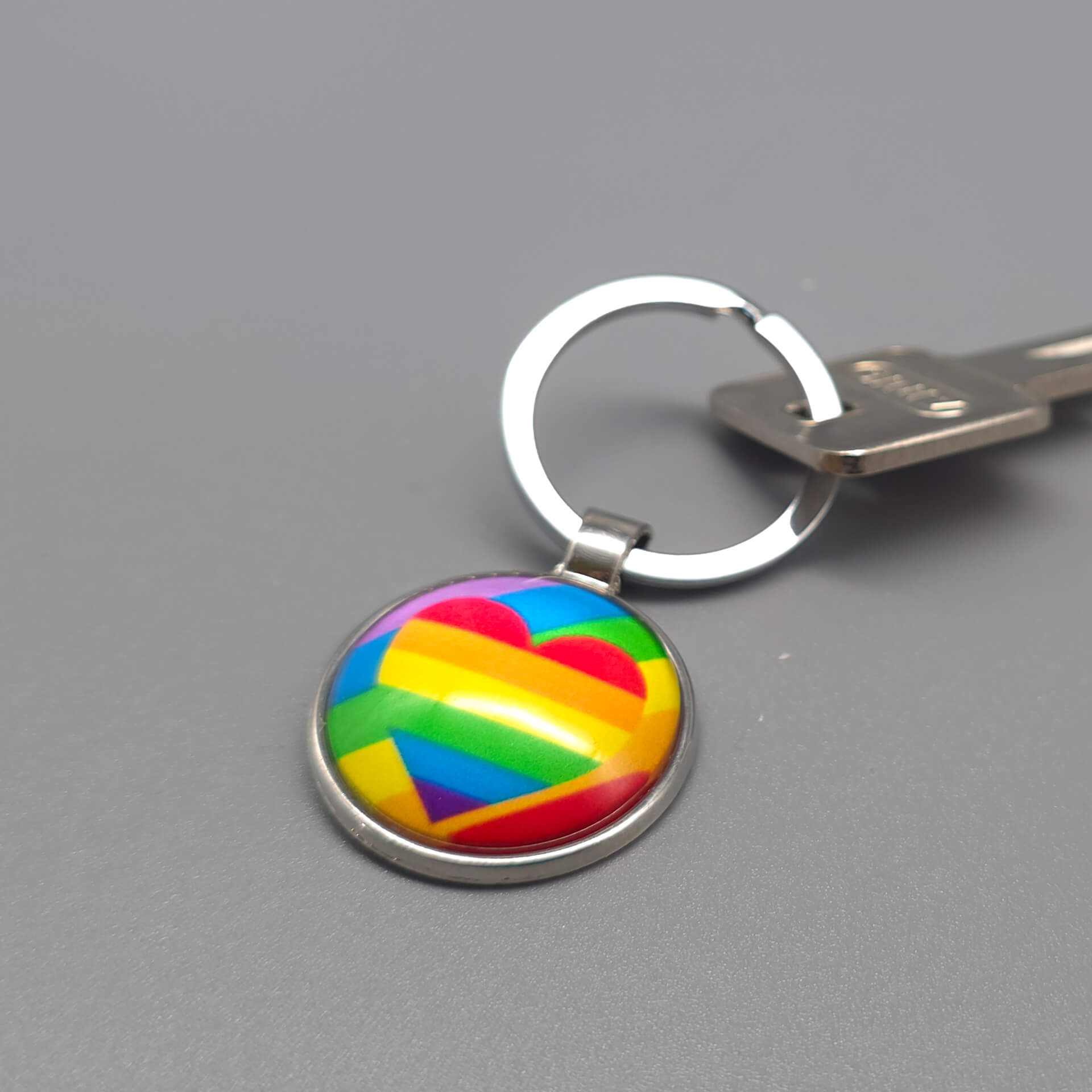 Regenbogen Herz Pride Schlüsselanhänger in Silber mit Glasdom, befestigt an einem Schlüssel – LGBTQ Geschenkidee für Alltag und CSD.