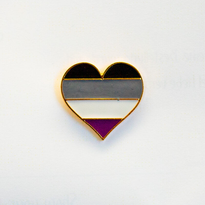 Vier horizontale Farbsegmente in Schwarz, Grau, Weiß und einem tiefen Lila definieren das Muster dieses asexuellen Community-Pins. Die silberne Umrandung verleiht dem herzförmigen Schmuckstück eine saubere Kontur.