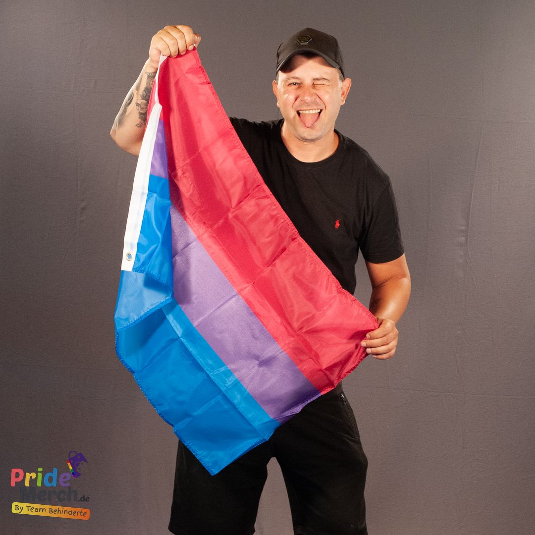 Tobias Wöltjen, bekannt als Drag Queen Joyce DeLone, präsentiert die kleine 90x60 cm Bisexuell-Flagge. Mit einem Augenzwinkern und herausgesteckter Zunge zeigt Tobias die Flagge, die ideal für Demos und als handliches Pride-Accessoire ist.