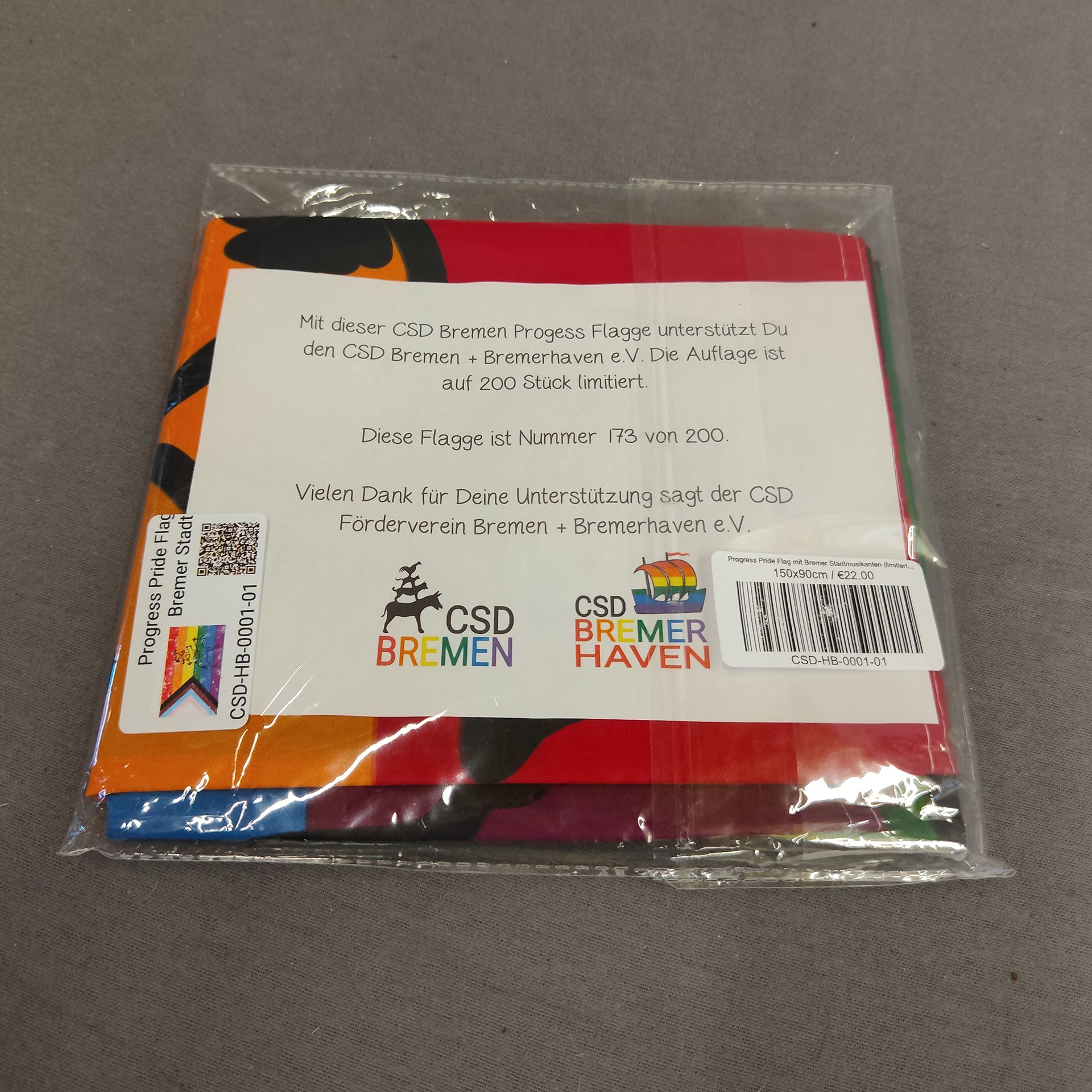 Die limitierte Progress Pride Flagge mit den Bremer Stadtmusikanten in der Originalverpackung. Obenauf liegt die nummerierte Urkunde, die die Echtheit und die Limitierung auf 200 Stück bestätigt.