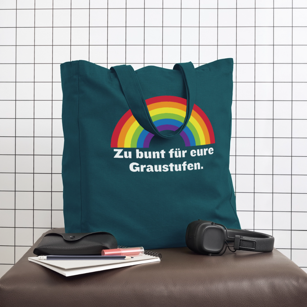 Stylische dunkelpetrole Statement Tote Bag auf einem braunen Hocker, dekoriert mit Kopfhörern