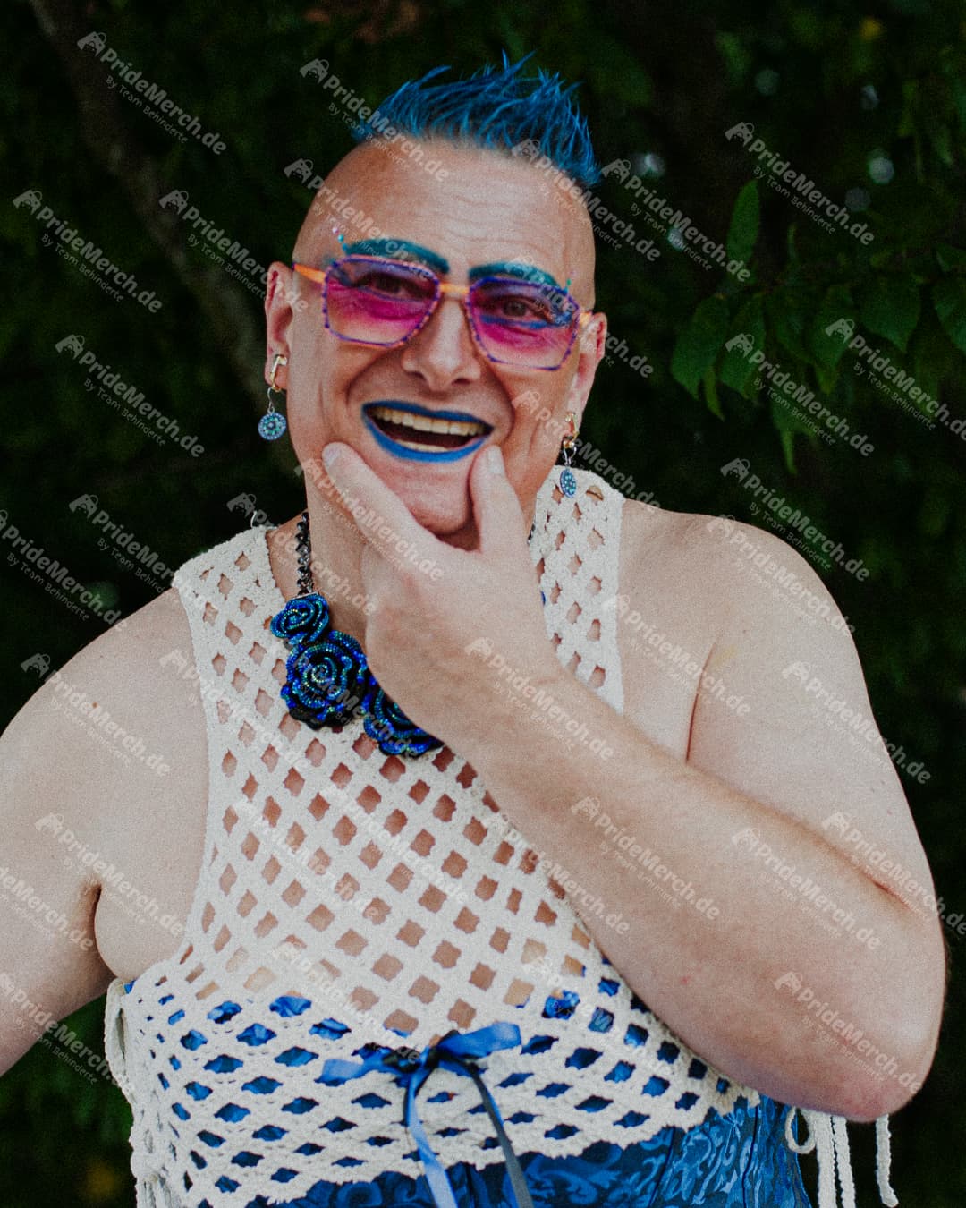 Porträt von Drag Queen Gina Petrolia mit leuchtend blauem Irokesenschnitt und passendem Lippenstift, kombiniert mit einer großen Sonnenbrille