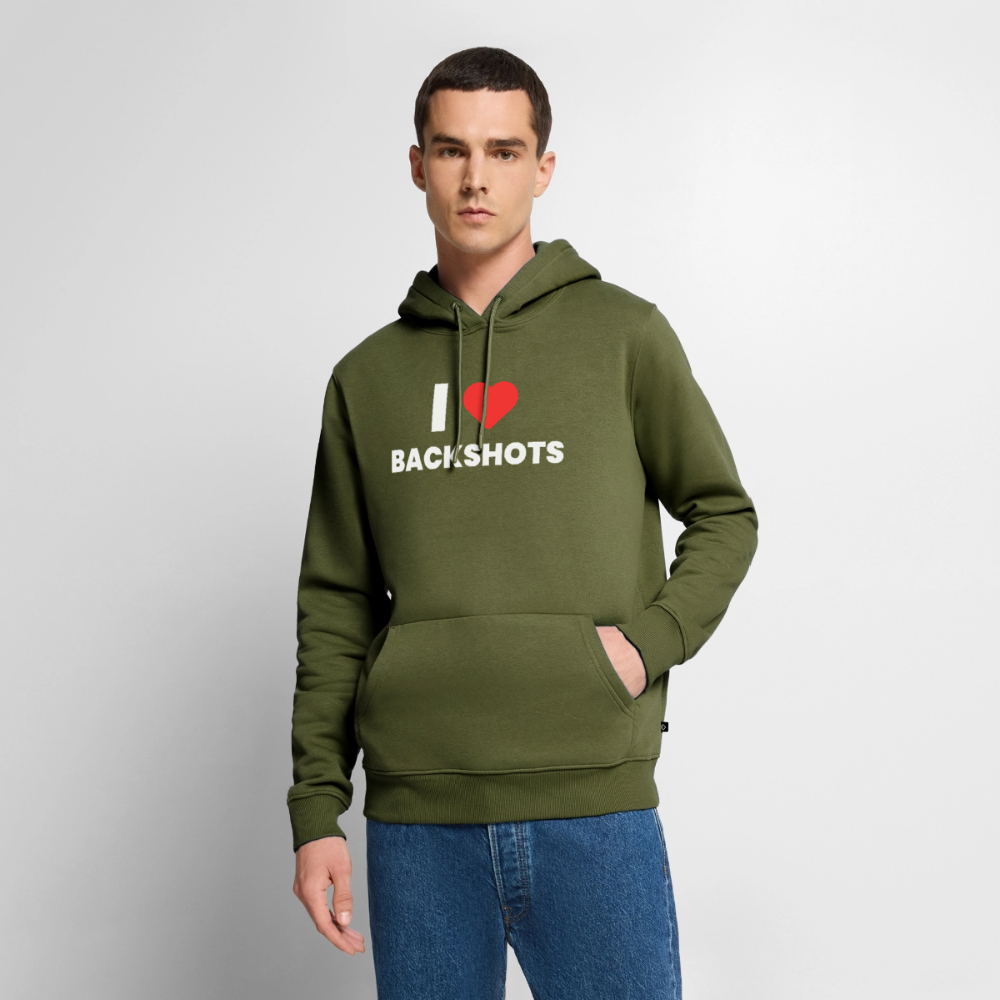 Das lächelnde Modell mit Bart posiert im khakifarbenen Winter-Hoodie. Das derbe „I ❤️ BACKSHOTS“-Meme-Design auf der Vorderseite verbindet derben Club-Humor perfekt mit einem bequemen Streetwear-Look.