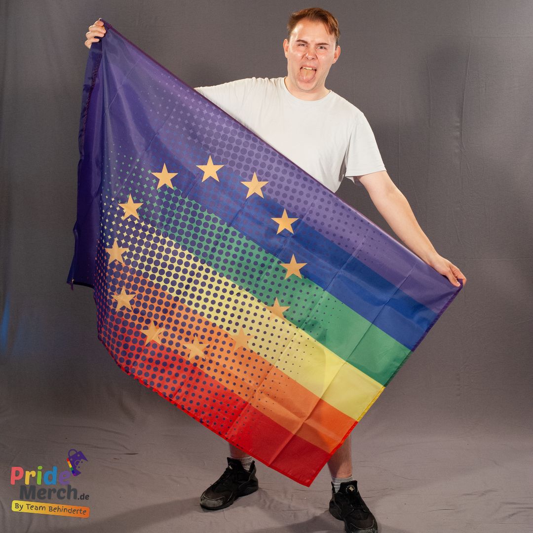 Das ehrenamtliche Laienmodell Luna Mattel (Bremer Dragqueen, Out of Drag) präsentiert gut gelaunt die Regenbogen Europa Pride Flagge im Fotostudio. Die 150x90 cm große Polyester-Fahne zeigt die europäischen Sterne im fließenden Übergang mit dem klassischen LGBTIQ-Farbschema.