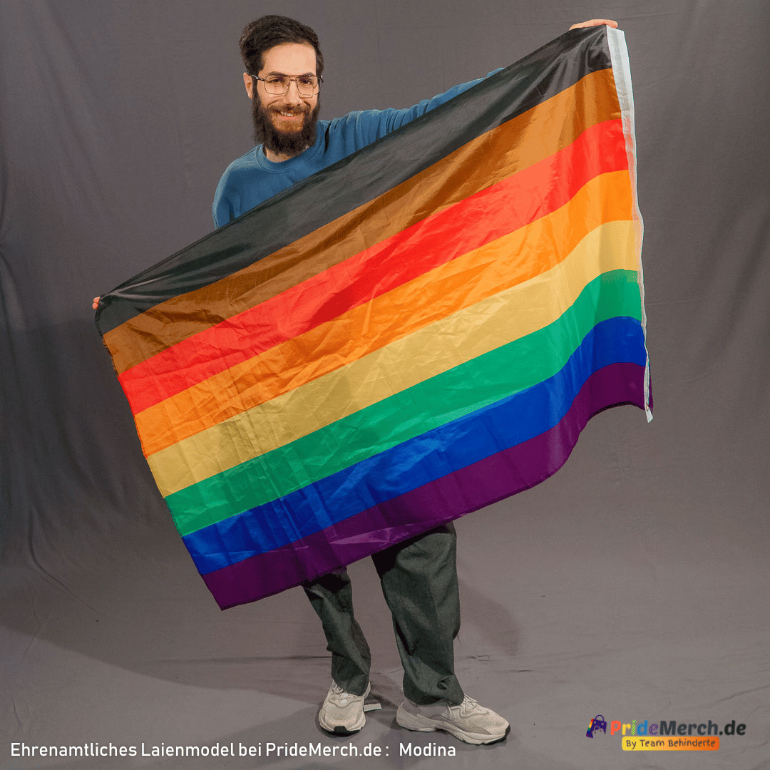 Das ehrenamtliche Laienmodell Modina hält lächelnd die 150x90 cm große Philadelphia Pride-Flagge im Fotostudio vor dem Körper aus. Die acht horizontalen Streifen inklusive Schwarz und Braun sind vollständig sichtbar.
