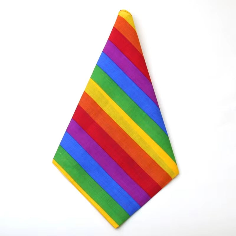 Das quadratische Bandana ist diagonal zu einem klassischen Halstuch gefaltet, sodass es ein spitzes Dreieck bildet. Die breiten Regenbogenstreifen verlaufen nun schräg über den Stoff und setzen ein klares, sichtbares Pride-Statement.