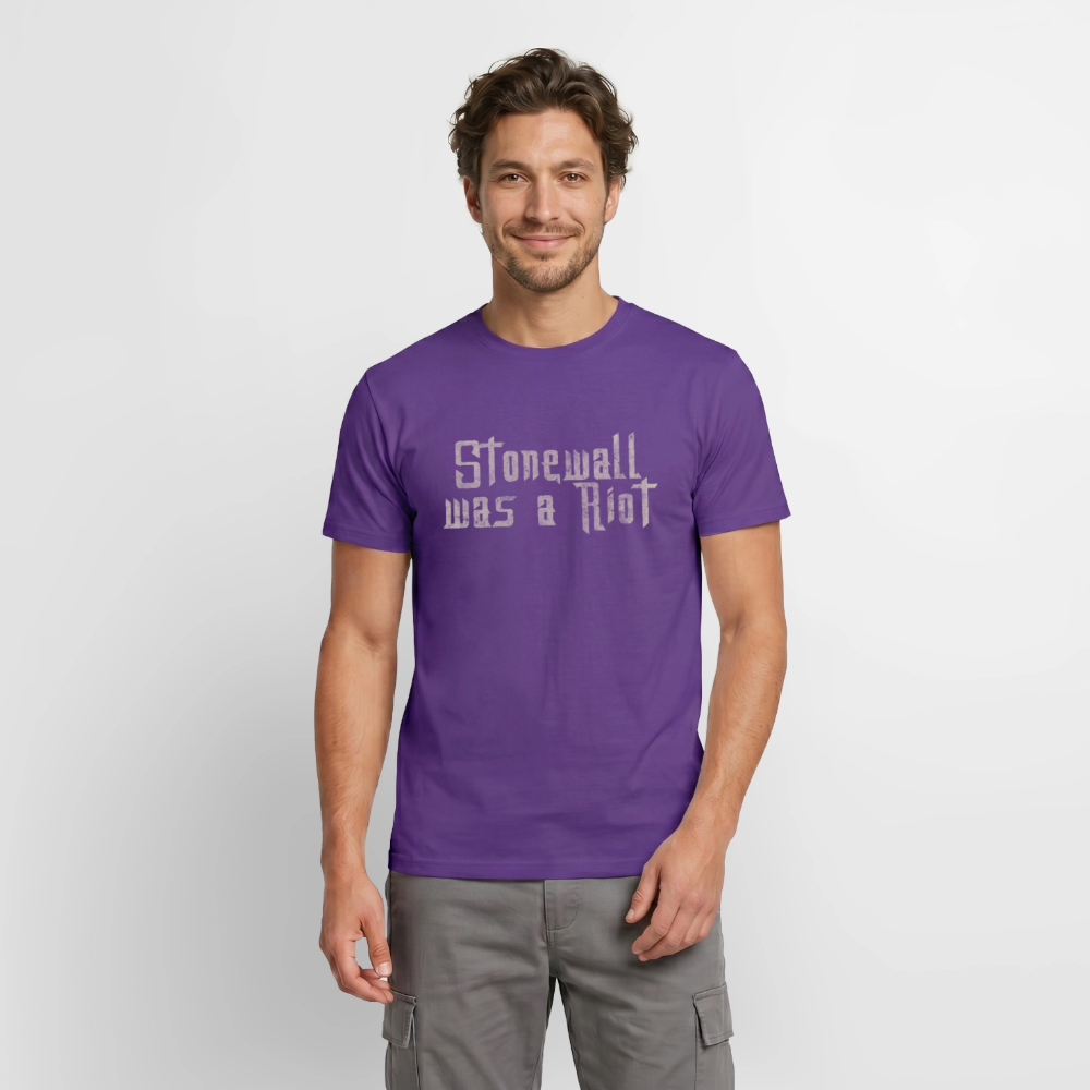 Ein Model präsentiert das lila Shirt. Der helle, verwitterte Schriftzug steht für die Solidarität mit den Wurzeln der LGBTIQ-Bewegung und gegen das Vergessen der Geschichte.