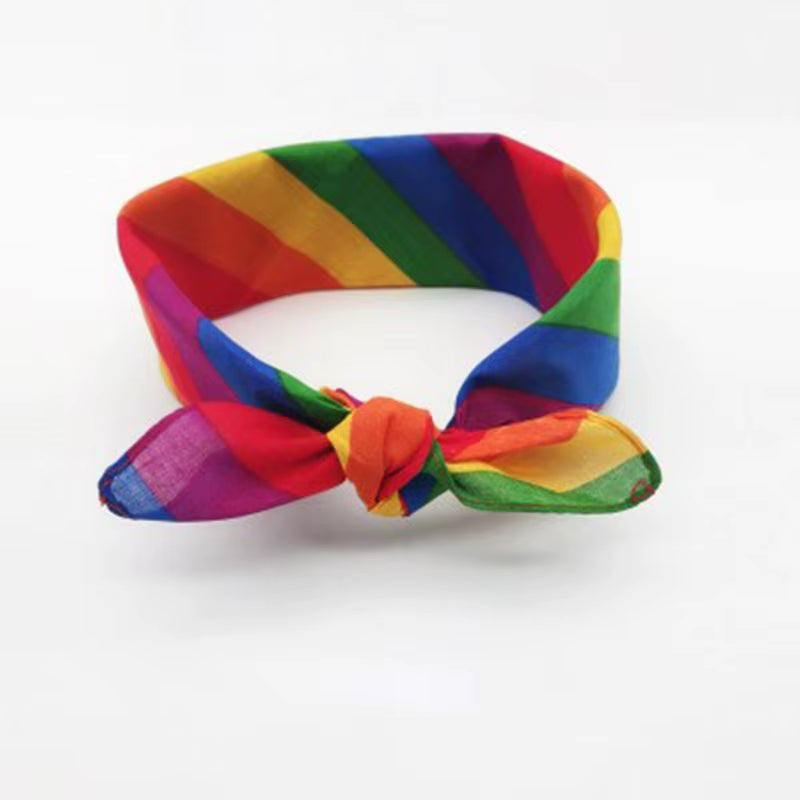 Das bunte Tuch ist schmal zusammengeschlagen und zu einem sportlichen Stirnband mit einem markanten Knoten in der Mitte gebunden. Ein praktisches LGBTQ-Accessoire, bei dem die Regenbogenfarben dynamisch ineinandergreifen.