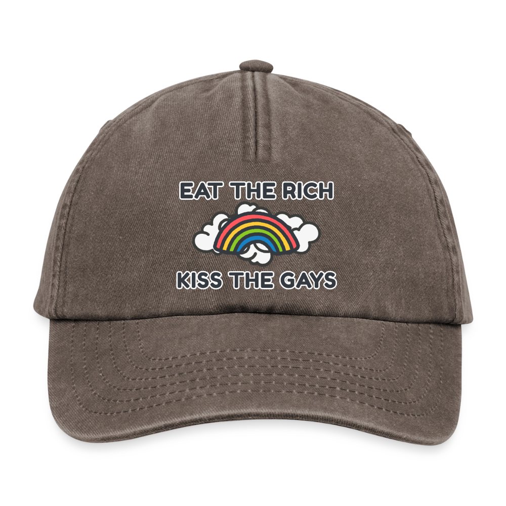 Auf der verwaschenen braunen Cap prangt unmissverständlich der Satz „Eat The Rich Kiss The Gays“. Die Kombination aus fetter Schrift und comic-haften Regenbogen-Wolken setzt ein starkes politisches Zeichen für die queere Community.