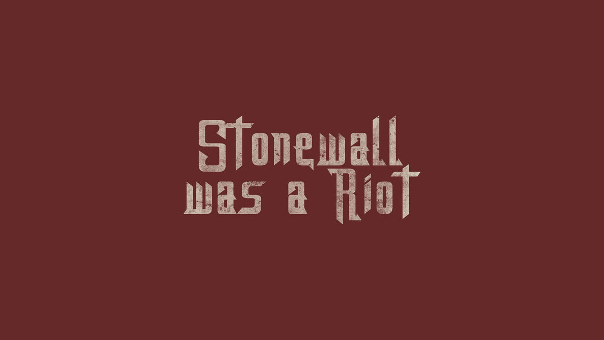 Zentrierter Schriftzug „Stonewall Was A Riot“ in gebrochener, rau wirkender Typografie auf dunkelrotem Hintergrund. Die hellbeigen, leicht verwitterten Buchstaben erinnern an historische Protestplakate und verweisen auf die Stonewall-Aufstände von 1969 sowie den Ursprung der LGBTIQ-Pride-Bewegung.