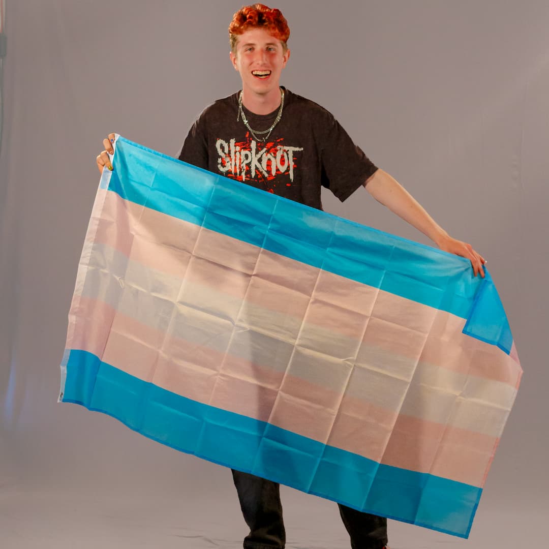 Einer der Initiatoren von PrideLAB, präsentiert die große Trans-Pride-Flagge in 150x90 cm. Die Farben Hellblau, Rosa und Weiß des robusten Polyester-Stoffs sind klar erkennbar.
