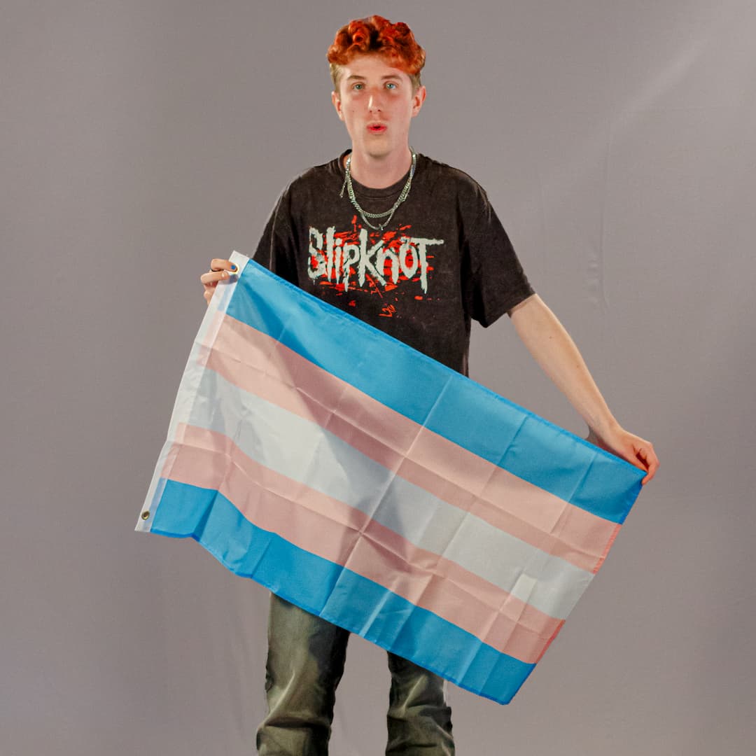 Einer der Initiatoren von PrideLAB, präsentiert die kleine Trans-Pride-Flagge in 90x60 cm. Die Farben Hellblau, Rosa und Weiß des robusten Polyester-Stoffs sind klar erkennbar.