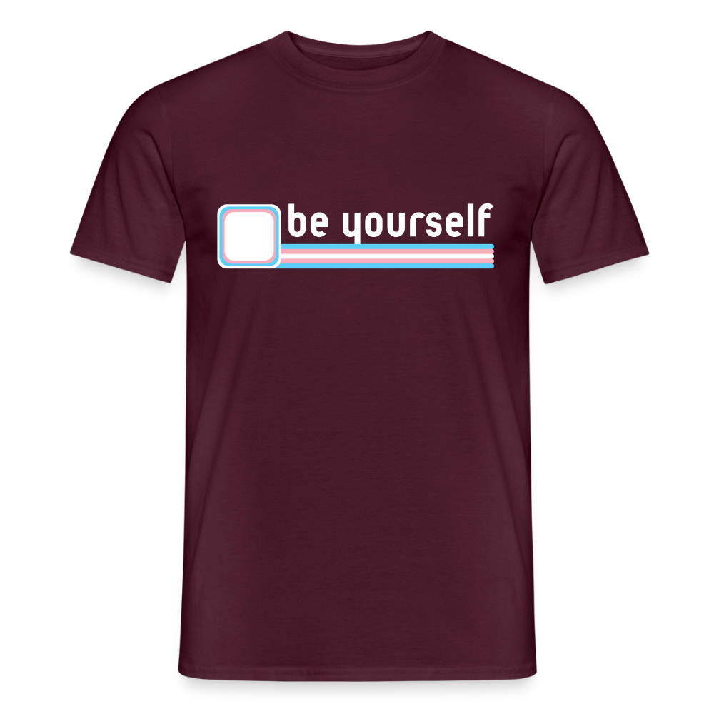 Das ziegelrote T-Shirt zeigt eine klare Botschaft für die Trans-Community. Freigestellt prangt der weiße "be yourself"-Schriftzug über den präzisen Linien der Trans-Flagge in Rosa, Hellblau und Weiß.